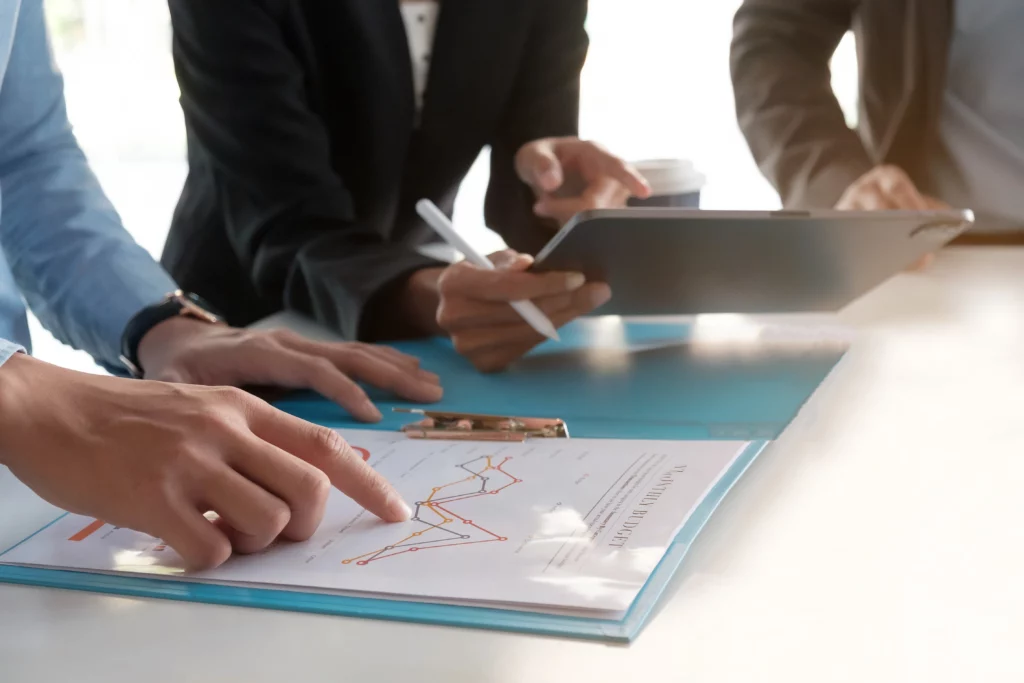 Three professionals in business attire reviewing a financial graph at a table, highlighting collaborative CFO support for law firm performance.